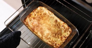 Kadın fırından sıcak kek ya da graten çıkarıyor.