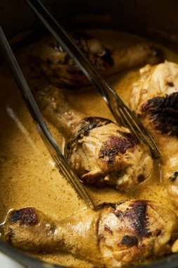 Hand holds afghani chicken in spicy sauce with cream and yogurt. Cucumber and sour cream salad on the background. High quality photo
