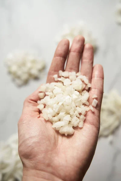 Small diced or finely chopped onions on mans hand. Photo show how does onion sliced into small cubes or sliced and diced onions look like. High quality photo