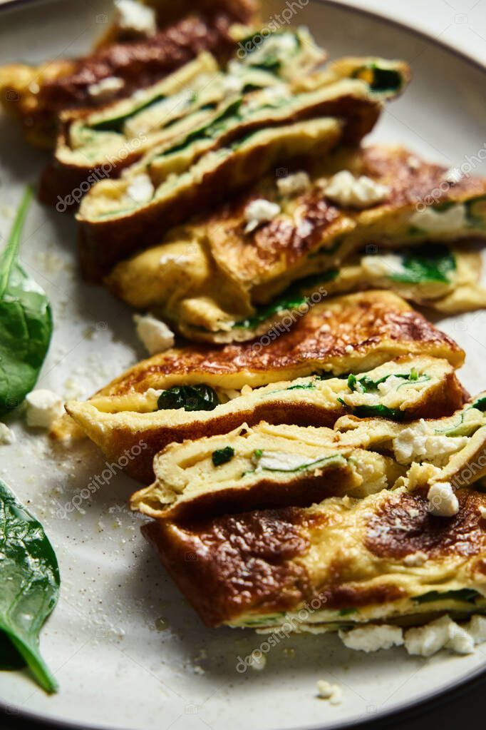Primer plano de tortilla plegada en rodajas rellena de espinacas y feta