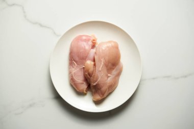 İki çiğ tavuk filetosu ya da beyaz tabakta tavuk göğsü. Beyaz ve temiz mermer arka plan. Hazırlanmaya ve pişirmeye hazır. Sağlıklı ve az yağlı. Uzayı kopyala Üst Manzara. - Evet. Yüksek kalite fotoğraf