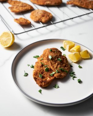 Beyaz tabakta limonlu fırında tavuk şnitzel. Arka planda ekmek kırıntılarıyla pişmiş şnitzeli diz ya da ızgara yap. Yüksek kalite fotoğraf