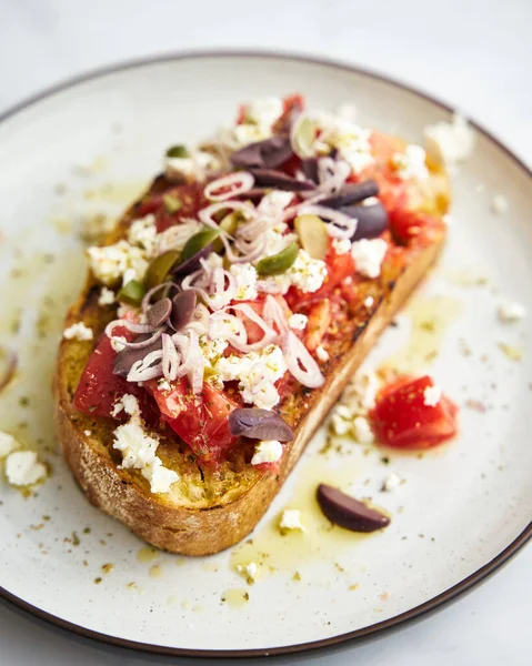 stock image dakos salad traditional Greek salad with soaked and crunchy barley rusks or bread, topped with juicy tomatoes, feta cheese, onions, olives, and a drizzle of olive oil. Popular apetizer. High quality