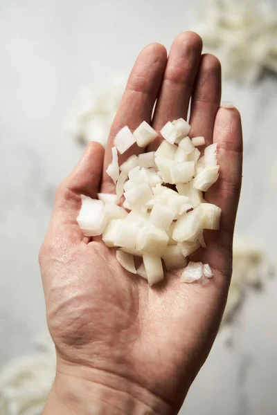 Medium diced onions on mans hand. Photo show how does onion sliced into medium cubes sliced and diced onions look like. High quality photo