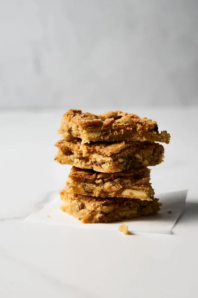 Stack of squares of Blondie cookies with pecan nuts on white marble countertop. White chocolate sweet and tasty, chewy cookie bars. High quality photo