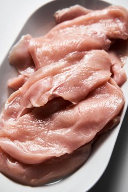 Çiğ tavuk filetosu beyaz mermer mutfak tezgahında oval bir tabakta şnitzel şeklinde kesilmiş. Yüksek kalite fotoğraf