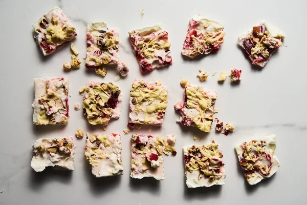 stock image Healthy Frozen Greek Yogurt bars with strawberry with lime zest, nuts and white chocolate. Homemade sweet dessert on white marble background. Top view, bright high key food photo. High quality photo