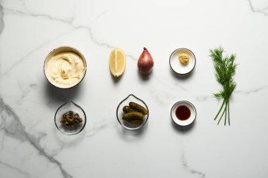 Beyaz mermer arka planda klasik Tatar sosu malzemeleri. Dereotlu mayonez ve kapari artı limon, soğanlı soğan. Worcester sosu ve Dijon Hardalı. Üst manzaralı yemek fotoğrafı. Flatlay. Yüksek kalite