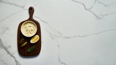 Beyaz mermer arka planda tahta üzerinde klasik Tatar sosu malzemeleri. Dereotlu mayonez ve limonlu salatalık turşusu. Üst manzaralı yemek fotoğrafı. Flatlay Yüksek Kaliteli Fotoğraf