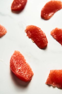 Soyulmuş ve dilimlenmiş, beyaz mermer tezgahın üzerinde greyfurt parçalarına ayrılmış. Parlak, hey-tuşlu dikey fotoğraf. Yüksek kalite fotoğraf