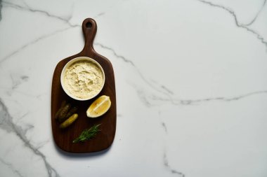 Beyaz mermer arka planda tahta üzerinde klasik Tatar sosu malzemeleri. Dereotlu mayonez ve limonlu salatalık turşusu. Üst manzaralı yemek fotoğrafı. Flatlay Yüksek Kaliteli Fotoğraf