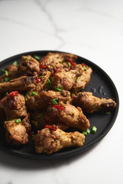 Çin tuzu ve biberli tavuk kanadı. Kızarmış tavuk kanadı, tuzlu ve biberli sebzeler ve soğan, sarımsak ve biberle çabucak sotelendi. Yüksek kalite