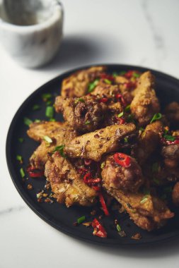 Çin tuzu ve biberli tavuk kanadı. Kızarmış tavuk kanadı, tuzlu ve biberli sebzeler ve soğan, sarımsak ve biberle çabucak sotelendi. Yüksek kalite