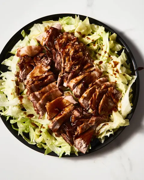 Çin Soya Domuzu. İstiridye ve soya sosuyla pişirilmiş domuz eti ve şeker. Buzdağı salatasında servis ediliyor. Yüksek kalite fotoğraf