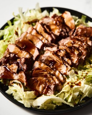 Çin Soya Domuzu. İstiridye ve soya sosuyla pişirilmiş domuz eti ve şeker. Buzdağı salatasında servis ediliyor. Yüksek kalite fotoğraf