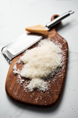 Tahtada rendelenmiş parmesan peyniri. Beyaz, parlak ve temiz bir arkaplan. Yüksek kalite fotoğraf.