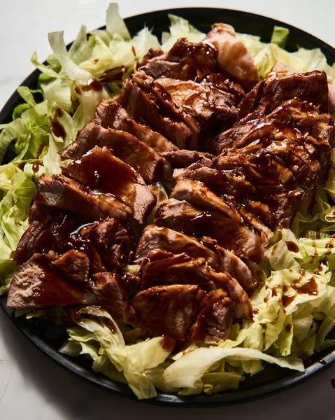 Çin Soya Domuzu. İstiridye ve soya sosuyla pişirilmiş domuz eti ve şeker. Buzdağı salatasında servis ediliyor. Yüksek kalite fotoğraf