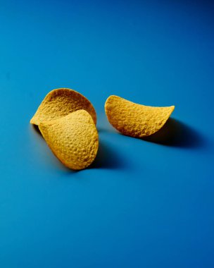 Mavi arka planda altın ve kabuklu patates cipsi. Minimalist yemek fotoğrafı. Yüksek kalite fotoğraf