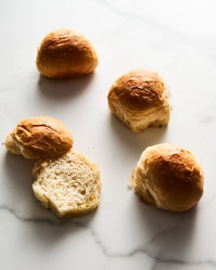 Burger Buns ya da tel askıda mini çörekler. Çok yumuşak, taze ev yapımı, tereyağlı. Beyaz mermer arka plan. Minimalist fotoğraf. Yüksek kalite fotoğraf