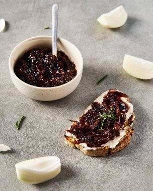 Lezzetli Fransız aperatifi taze pişmiş soğan konfetisi üzerine krem peynir ve kekik. Beton tavan arası geçmişi. Kahvaltı ya da öğle yemeği kompozisyonu. Yüksek kalite fotoğraf