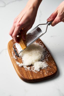 Adam ahşap bir tahtanın üzerinde ızgara parmesan peyniri tutuyor. Beyaz, parlak ve temiz bir geçmişi var. Yüksek kalite fotoğraf