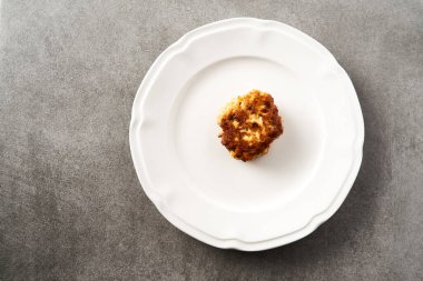 Beton arka planda beyaz tabakta mozzarella peynirli tek Altın Kahverengi Tavuk Pirzolası. Yüksek kalite fotoğraf