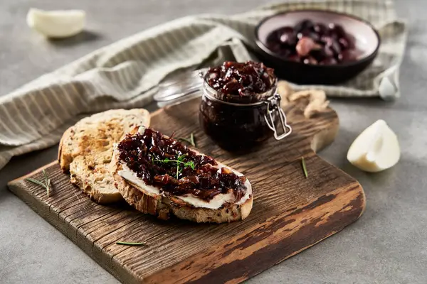 Lezzetli Fransız aperatifi taze pişmiş soğan konfetisi üzerine krem peynir ve kekik. Tahta ve kavanozla soğan reçeli. Beton tavan arası geçmişi. - Evet. Yüksek kalite fotoğraf