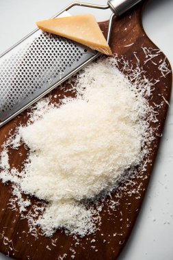 Tahtada rendelenmiş parmesan peyniri. Beyaz, parlak ve temiz bir arkaplan. Yüksek kalite fotoğraf.