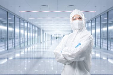 Worker wears medical protective suit or white coverall suit with mask and goggles arm crossed