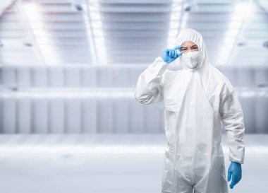 Worker wears medical protective suit or white coverall suit with mask and goggles 