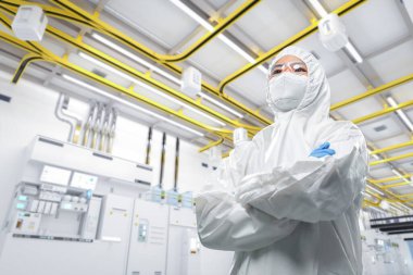 Worker or engineer wears protective suit or white coverall suit work in semiconductor manufacturing factory