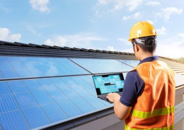 Ev çatısındaki güneş panelleriyle çalışan mühendis ev kullanımı için elektrik üretiyor.