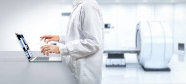 Doktor, hastane odasında MRI cihazı üzerinde çalışıyor.