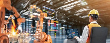 Teknisyen veya mühendis fabrikada robotik silahlarla çalışıyor.