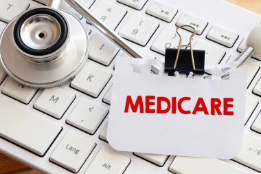 Klavyedeki steteskopun yanına yerleştirilmiş küçük bir kağıt parçasına MEDICARE kelimesi.