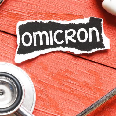 OMICRON kelime virüs steteskop yanında siyah bir kağıt parçası üzerinde.