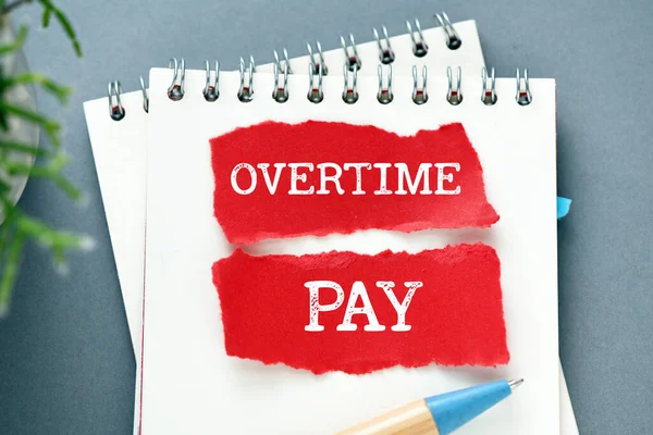 OVERTIME PAY words on small pieces of paper and a notebook.