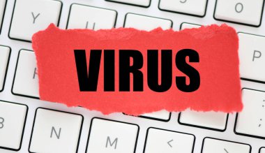 Beyaz bir bilgisayar klavyesine yerleştirilmiş kırmızı bir kağıt parçasında VIRUS kelimesi.