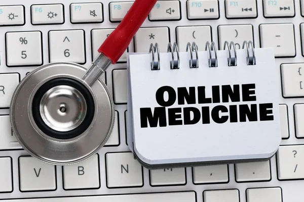 The words ONLINE MEDICINE on a small piece of paper next to a stethoscope.