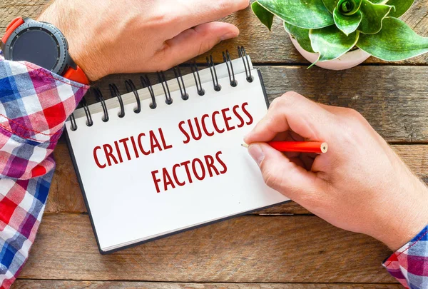 CRITICAL SUCCESS FACTORS in an office notebook on a wooden table.
