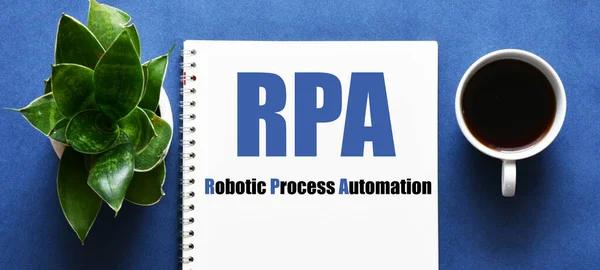 RPA (Robotic Process Automation) concept. Words in a notebook on a blue table.