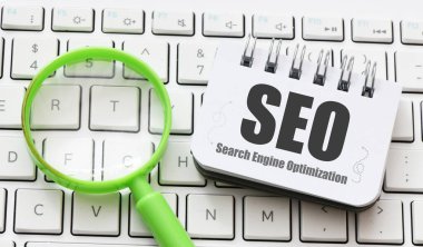 SEO Arama Motoru İyimser sözcükler bir ofis defterinde yeşil bir büyüteç yanında.