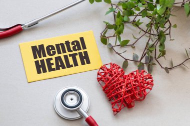 Stetoskop ve kalbin yanında küçük sarı bir kağıt parçasında MENTAL Sağlık Sözcüğü.