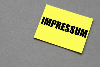Sarı kağıt ve gri arkaplan üzerine IMPRESSUM kelimesi.