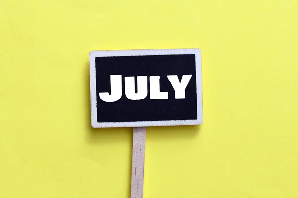 Λέξη Ιουλίου Ένα Μικρό Μαυροπίνακα Και Κίτρινο Φόντο — Φωτογραφία Αρχείου