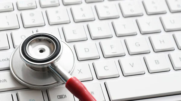 白色计算机键盘上的医疗听诊器 — 图库照片