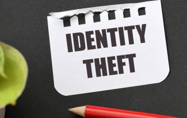 IDENTITY THEFT words on a piece of paper and a black table. clipart