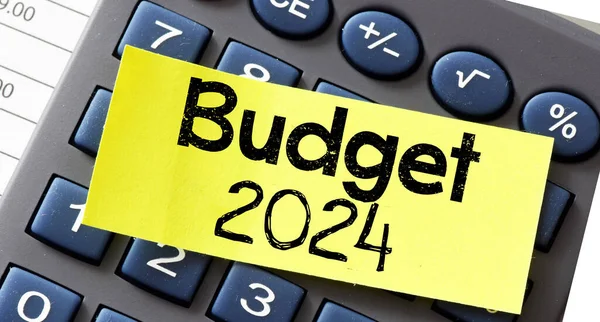 stock image BUDGET 2024 text on a small yellow piece of paper lying on top of the calculator. Concept for business. 