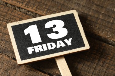 Tebeşir tahtası ve ahşap masa üzerinde 13 Cuma kelimesi.