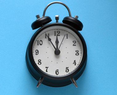 Mavi arkaplanda siyah alarm saati.